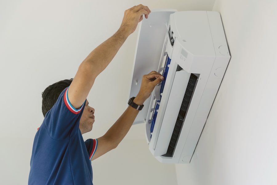 Engineer servicing a wall-mounted air conditioning unit